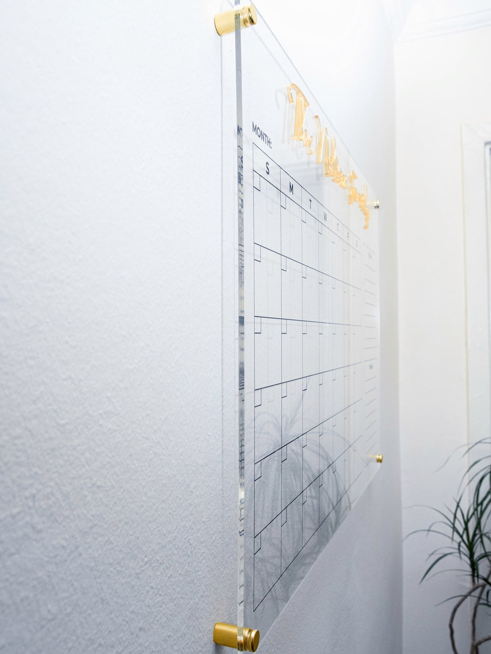Side angle showing the acrylic planner floating off the wall on gold standoffs