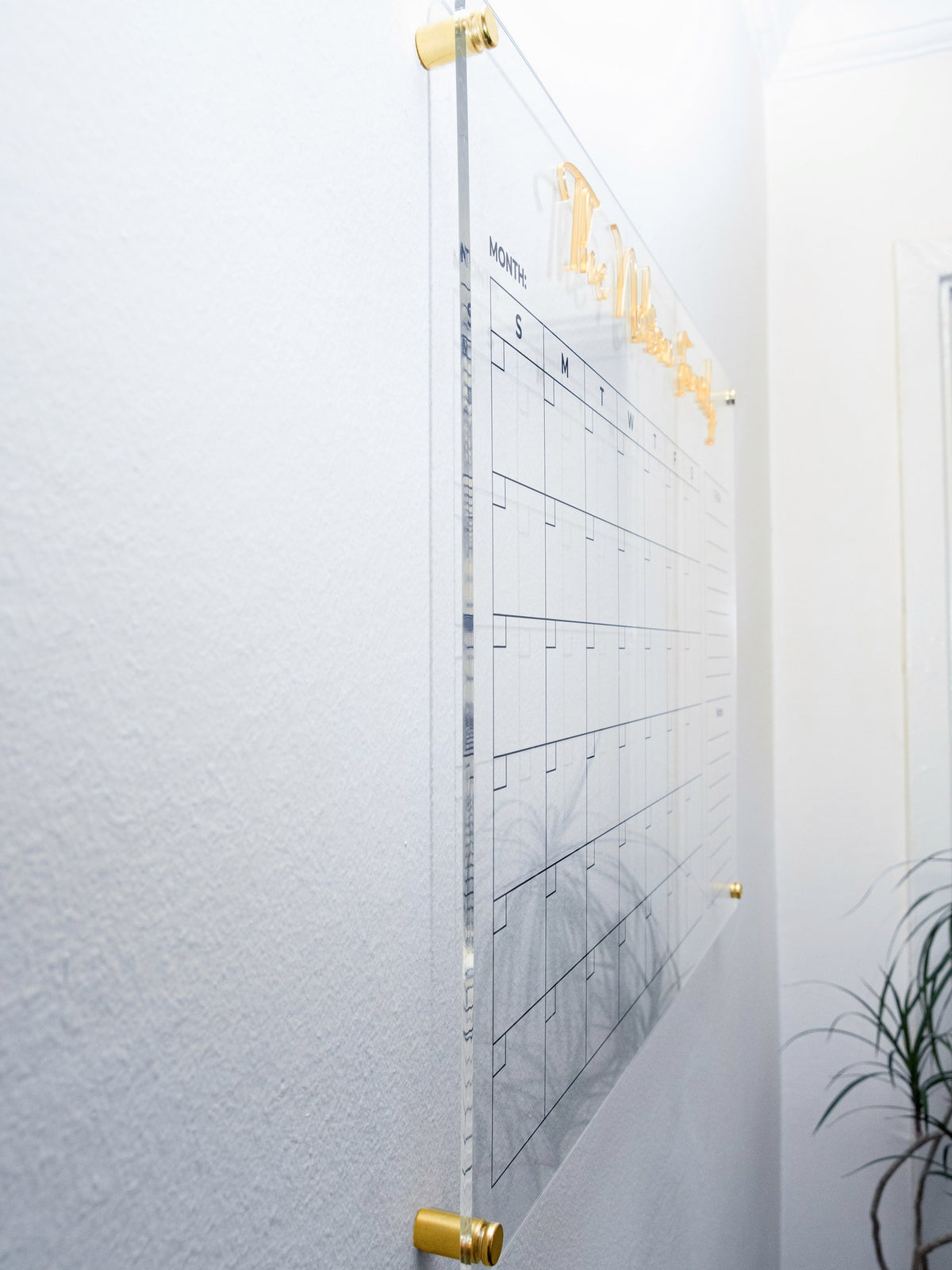 Side angle showing the acrylic planner floating off the wall on gold standoffs