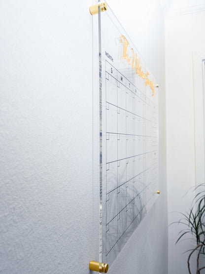 Side angle showing the acrylic planner floating off the wall on gold standoffs