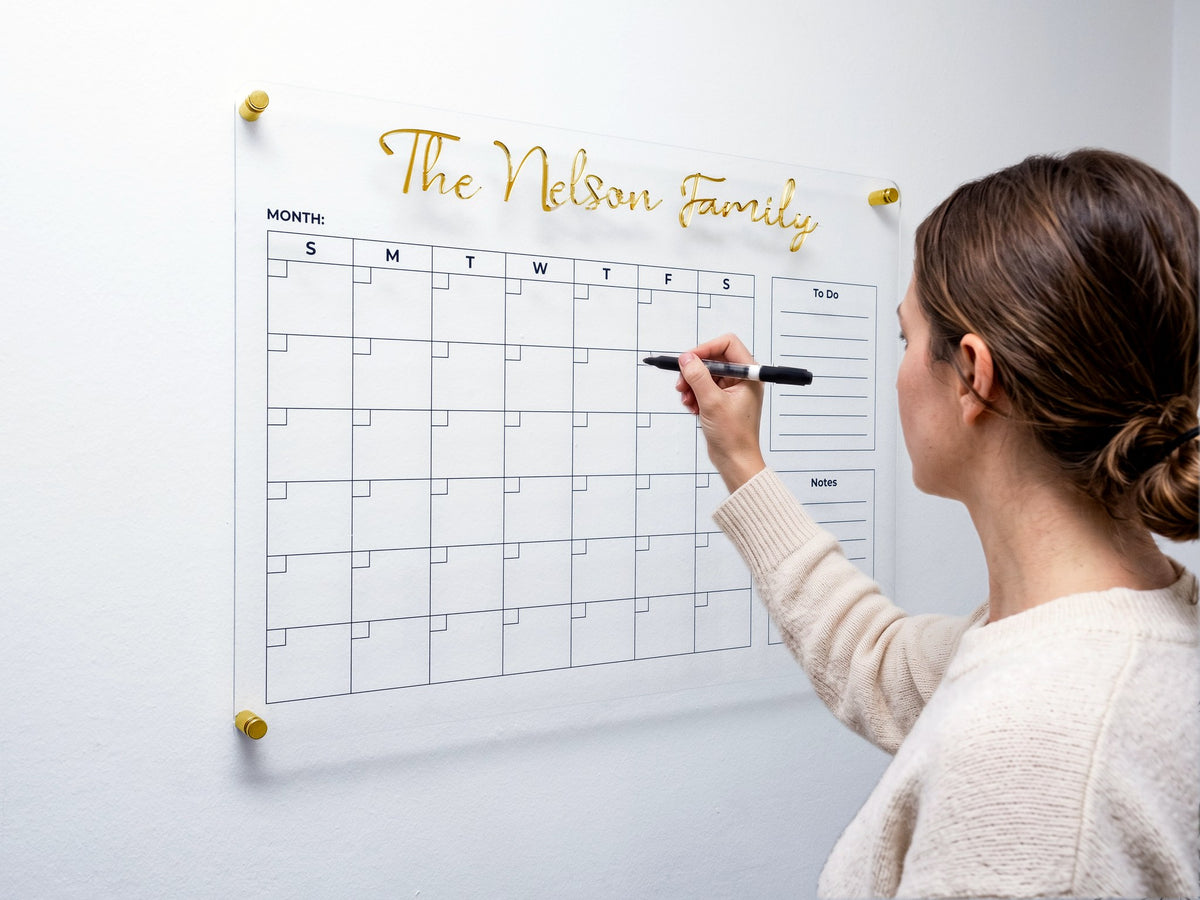 Close view of a woman filling in the acrylic dry erase wall calendar with a marker